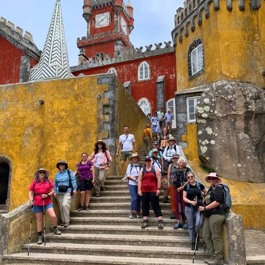A group of women stand on the steps of the National Palace of Pena in Portugal. They are on a hiking tour with Adventures in Good Company.