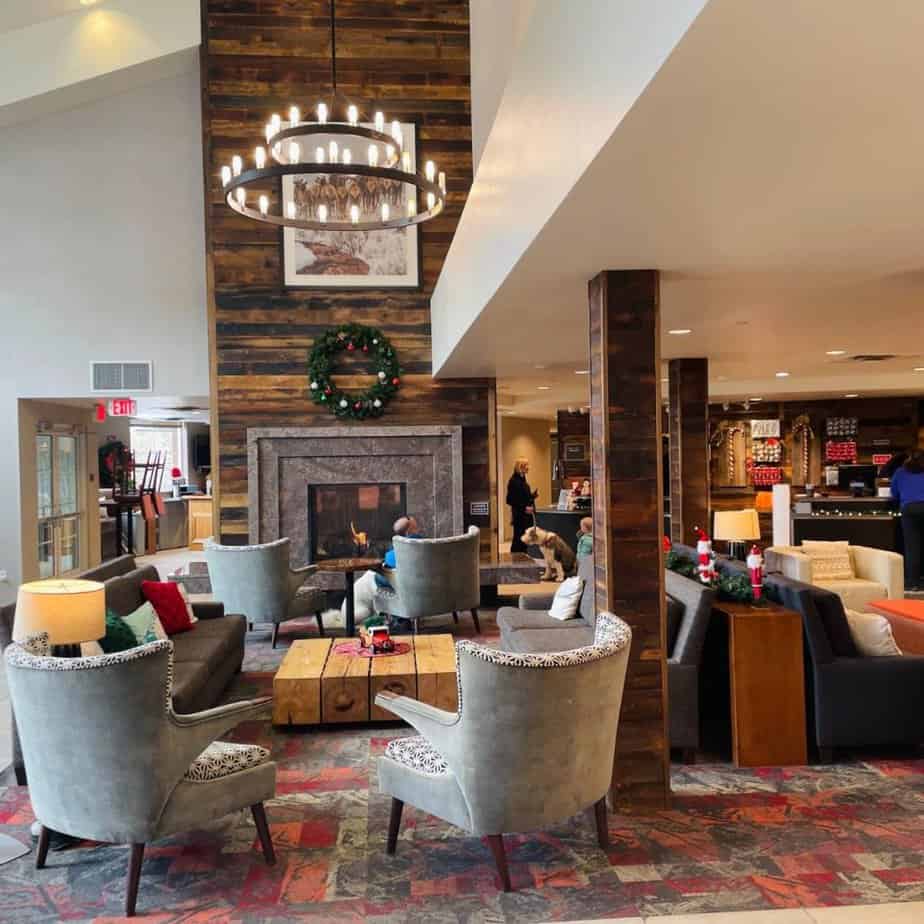 The lobby of the Breckenridge Residence Inn with a grouping of chairs in front of a fireplace, a vaulted ceiling and chandelier.