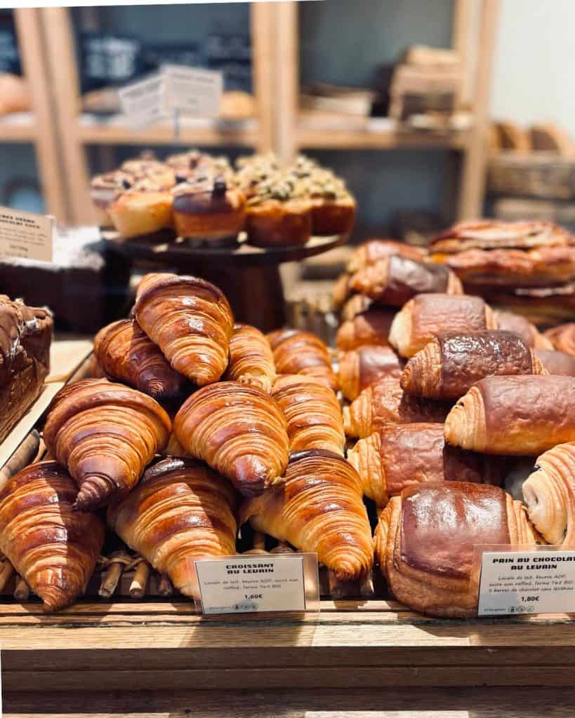 Butter croissants and chocolate croissants are piled on the counter of a Paris boulangerie.