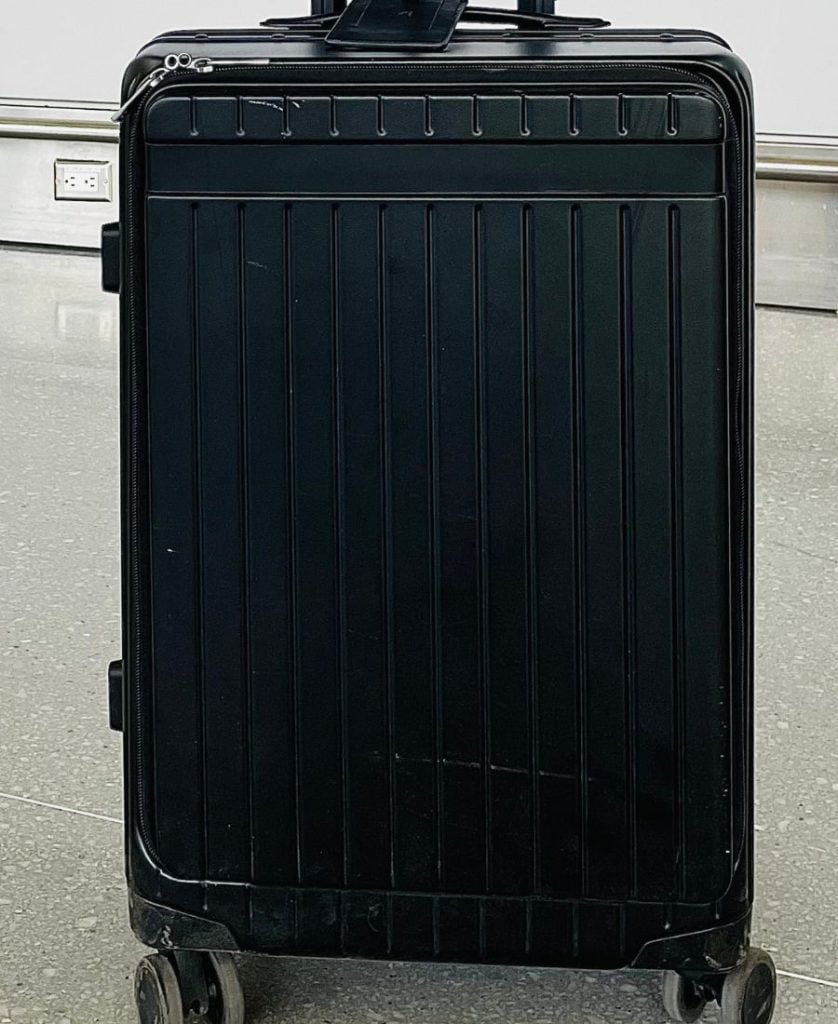 A black Carl Friedrik Carry-onX roller bag after use, with a few white scuffs visible on it.