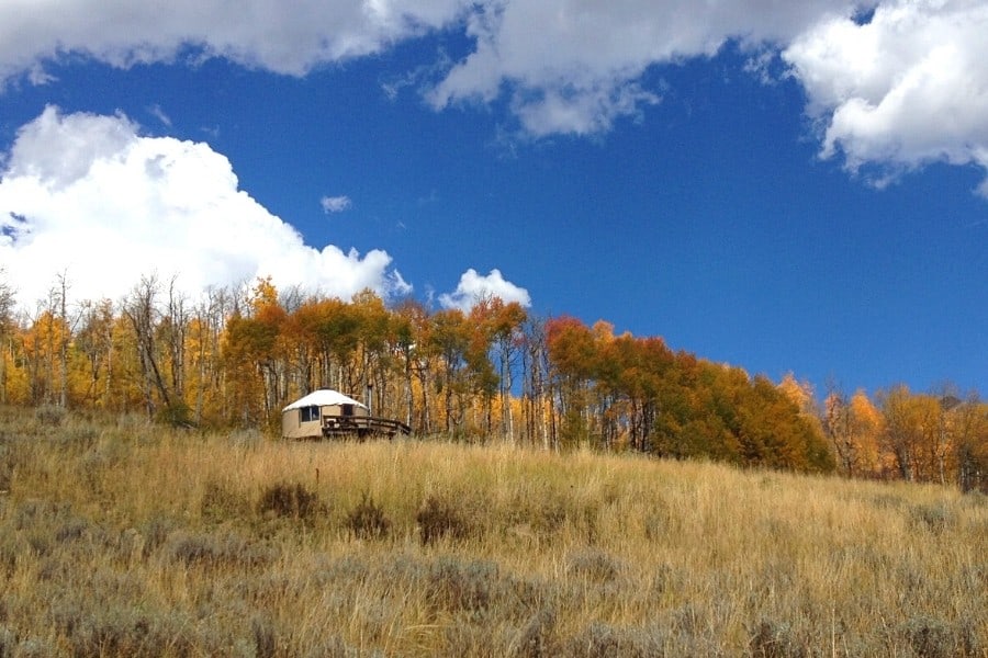 A Colorado yurt is set in a remote location with golden aspen trees beyond it