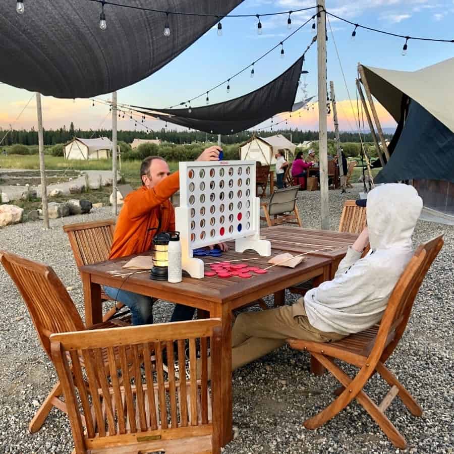 A father and son plan Connect Four at a table at Under Canvas Yellowstone
