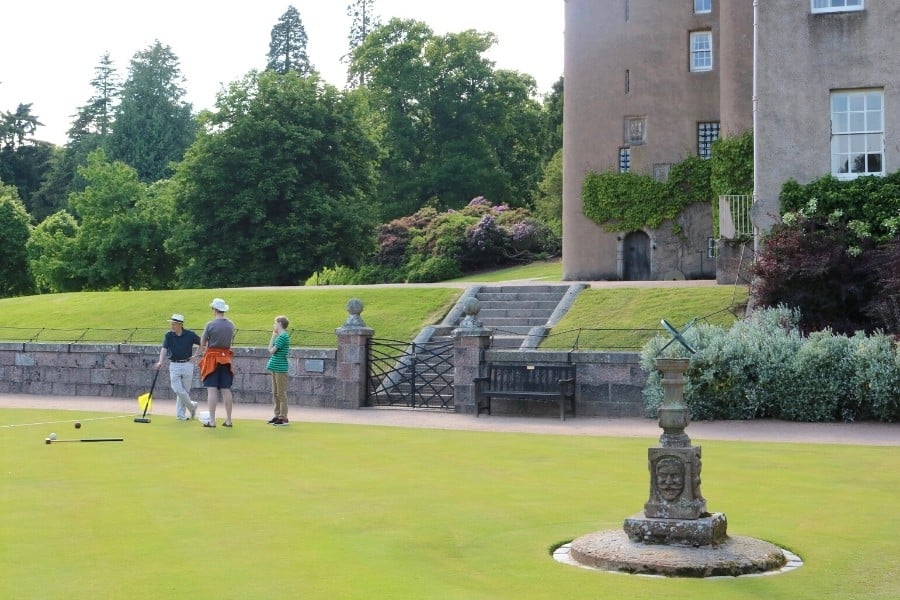 People stand on a croquet field at Crathes Castle in Scotland
