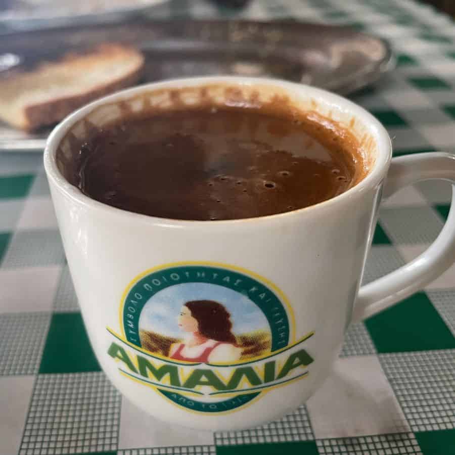 A small demi-tasse of Cypriot coffee sits a top a green and white checked tablecloth