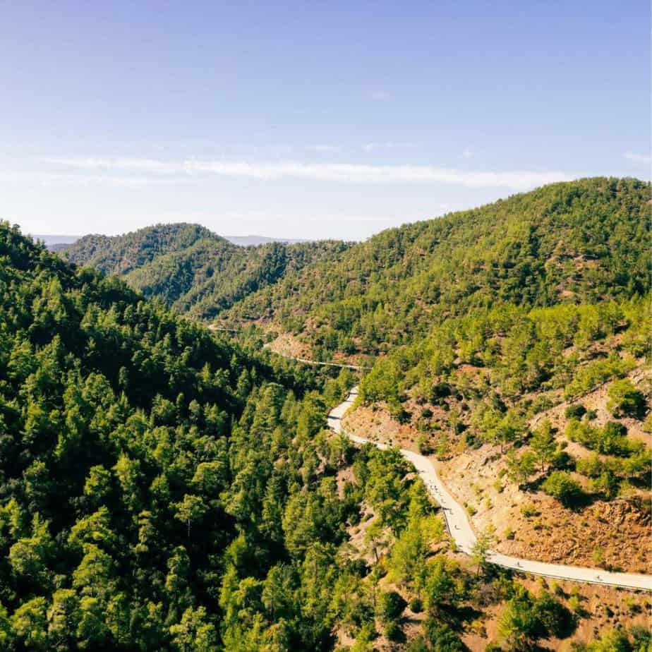 An aerial shot of a windy road through the Cyprus mountains with a line of cyclists along the route.