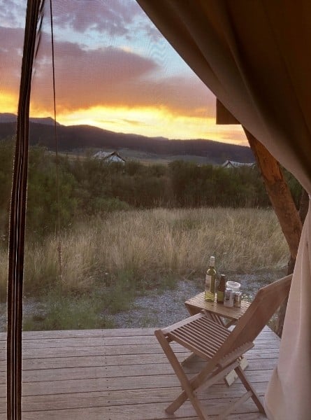 has a glass of wine. The sun sets beyond.