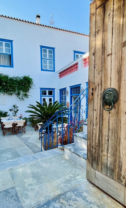 Pretty courtyard with wooden door and ornate knocker, in Hydra Greece