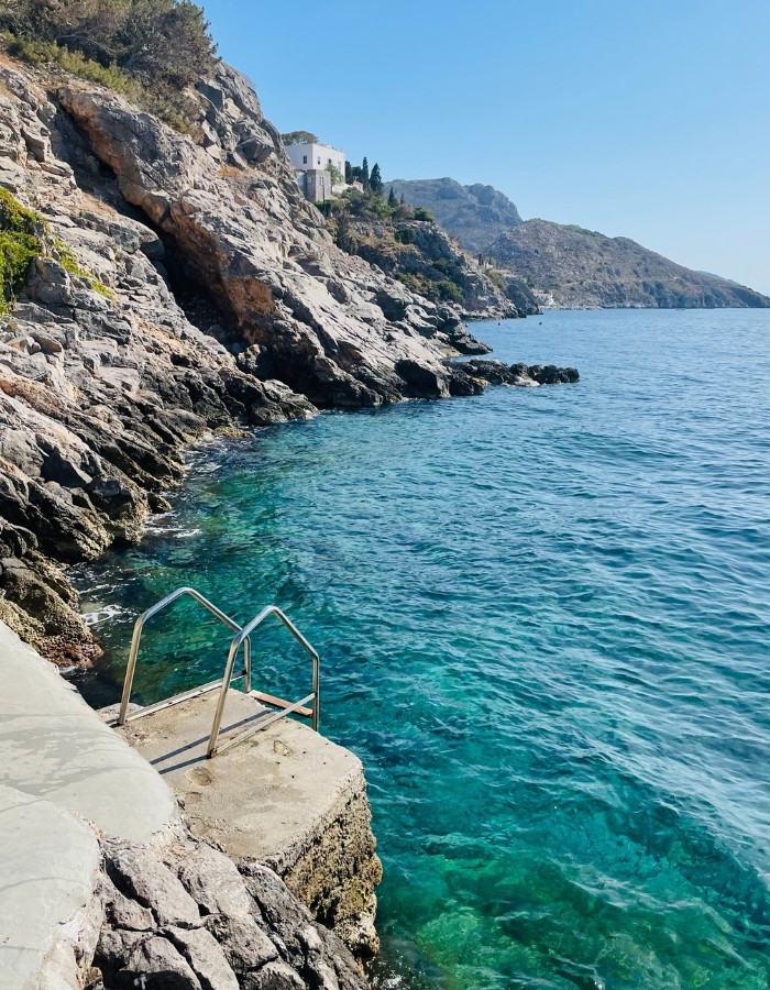 Swim Jetty at Hydronetta in Hydra Greece, with turquoise sea cliffs beyond