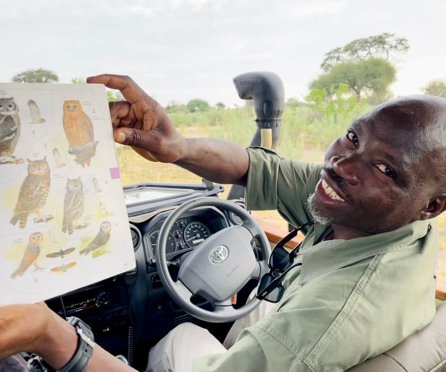 Ollie, a guide at Leroo La Tau safari lodge in Botswana holds a book with birds showing his favorite, a Pel's Fishing Owl.