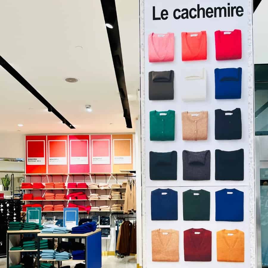 A wall of cashmere sweaters arranged by colour in the Monoprix Champs Elysees Paris store