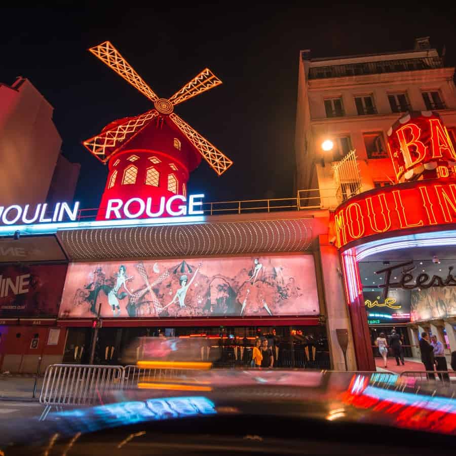 The exterior of the famous Paris Cabaret Moulin Rouge is pictured with its red lights and iconic windmill.