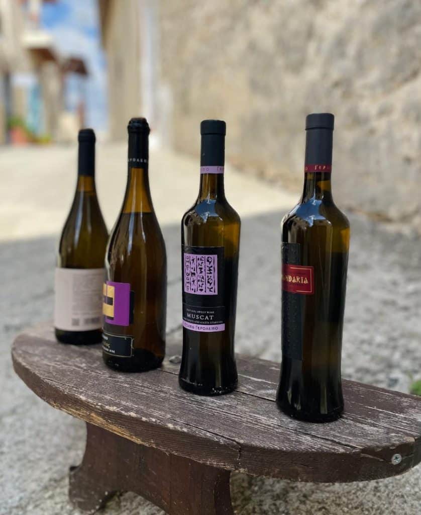 Four bottles of re wine are on a low table in a cobblestone laneway