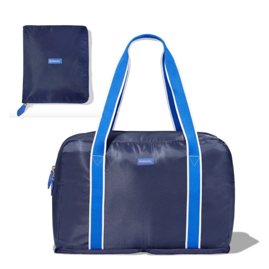 A navy and royal blue fold-up duffel bag by Paravel is shown against a white background, along with the small pouch it folds in to.