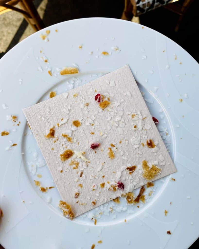 A plate is empty other than a sprinkling of croissant crumbs.