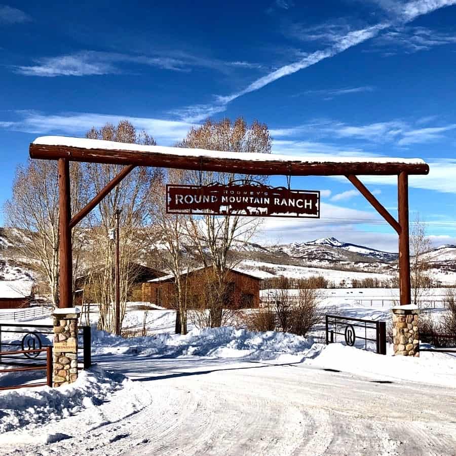 A ranch gate with blue skies and mountains beyond, in northern Colorado
