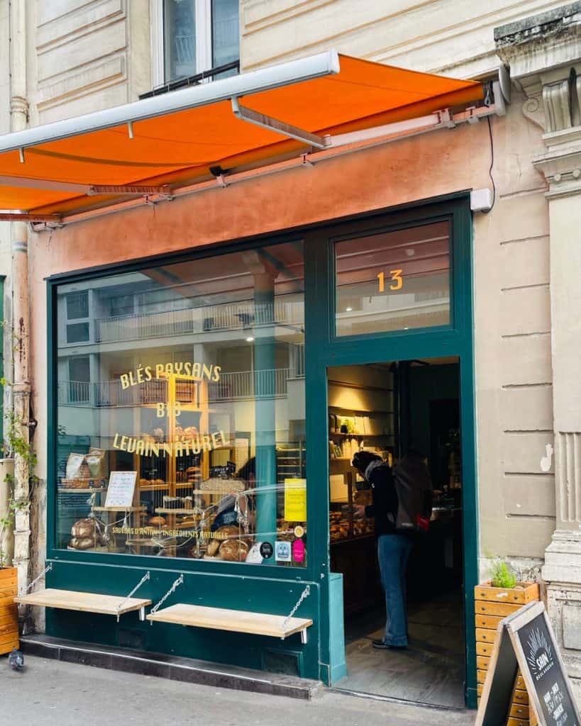 The entrance to a bakery on a Paris street with an orange awning overhead