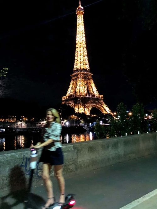 Susan Heinrich riding a scooter past the Eiffel Tower at night Susan Heinrich riding a scooter past the Eiffel Tower at night
