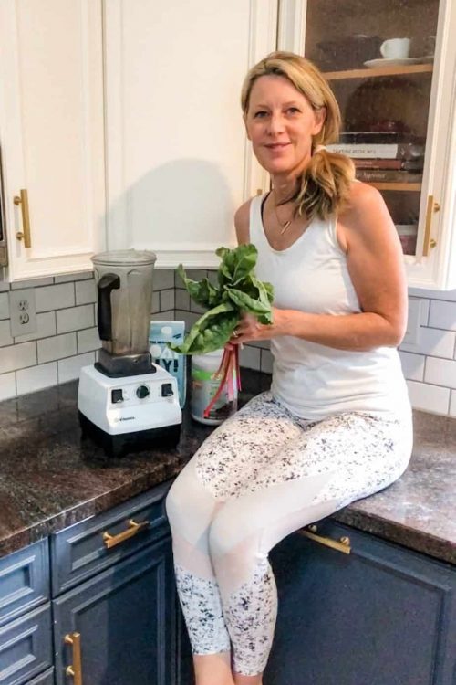 SH-fit-at-50_nutrition Susan Heinrich sits in her kitchen holding a handful of leafy greens