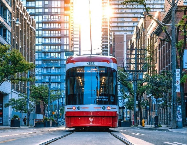A red streetcar travels past highrise buildings on downtown Toronto