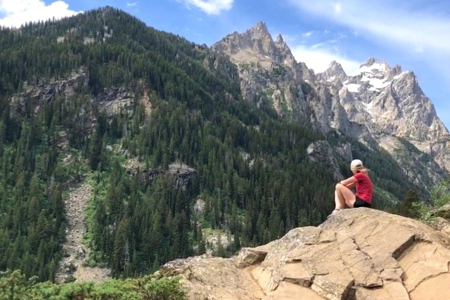 Susan Heinrich sitting on a rock and looking out at the view at Grand Teton National Park.