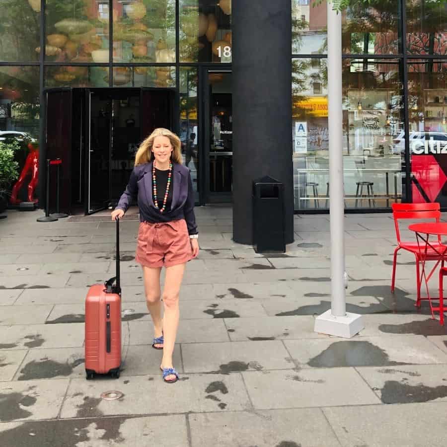 Susan Heinrich walks away from the CitizenM Bowery hotel with her Monos carry-on luggage