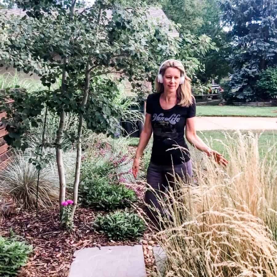 Susan Heinrich walks through a garden with white "beats" headphones on