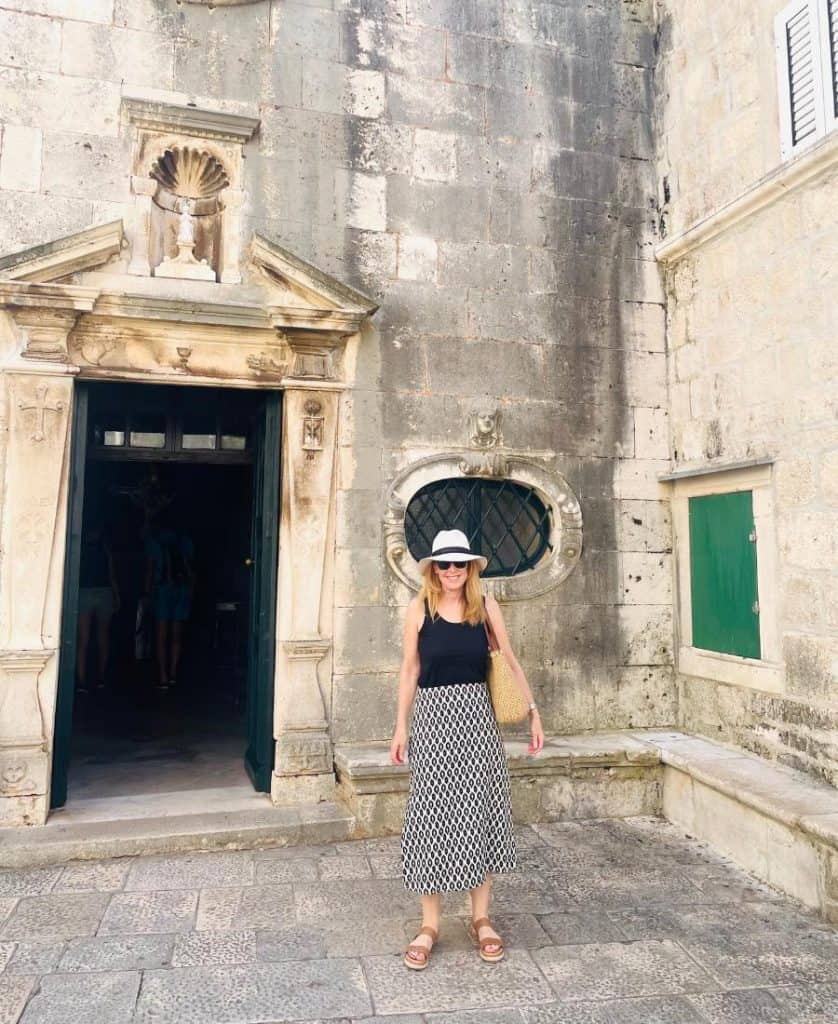 A woman stands in front of a medieval building in Korcula, Croatia.