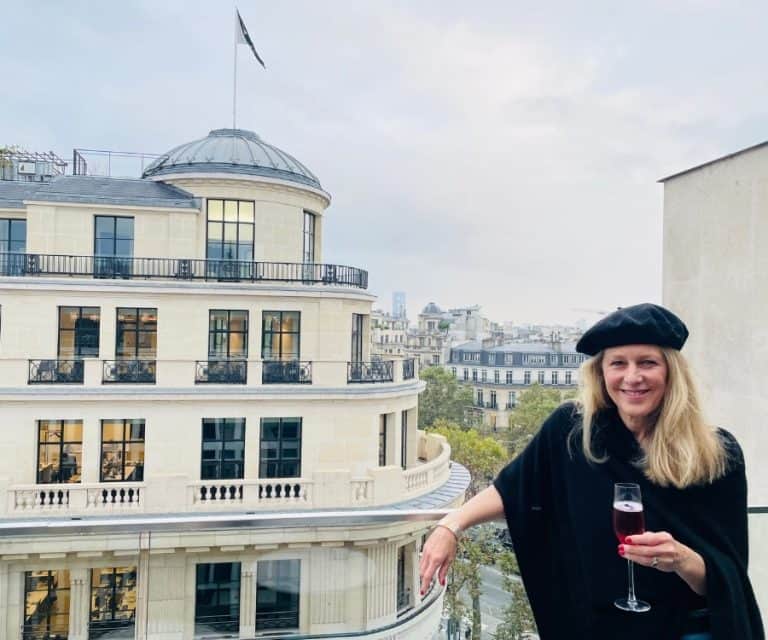 Susan Heinrich stands on a outdoor terrace in Paris near the Champs Elysees