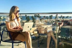 Susan Heinrich sits typing on a laptop and overlooking the Pacific Coast in L.A.