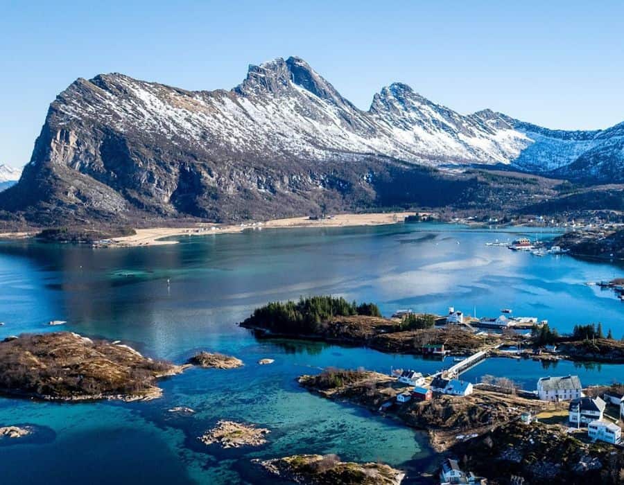 A few small buildings are visible in the Norwegian Arctic with hills beyond.