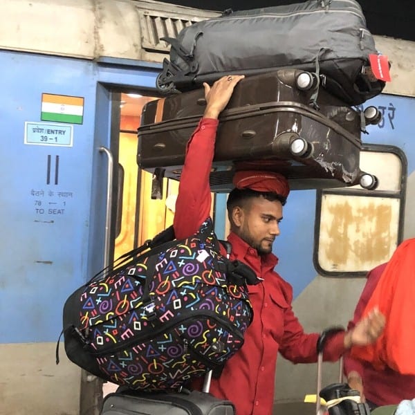 A porter carries luggage stacked on his head at a train station in India