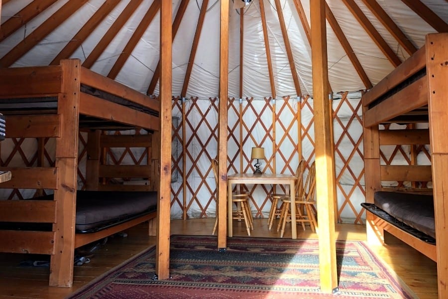 The inside of a Colorado yurt with simple wood bunkbeds and a table and chairs