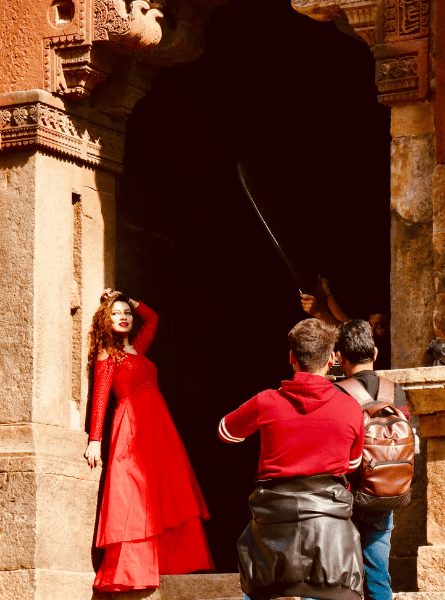 A woman poses in a red dress at a photo shoot at the Lodi Tomb in Delhi