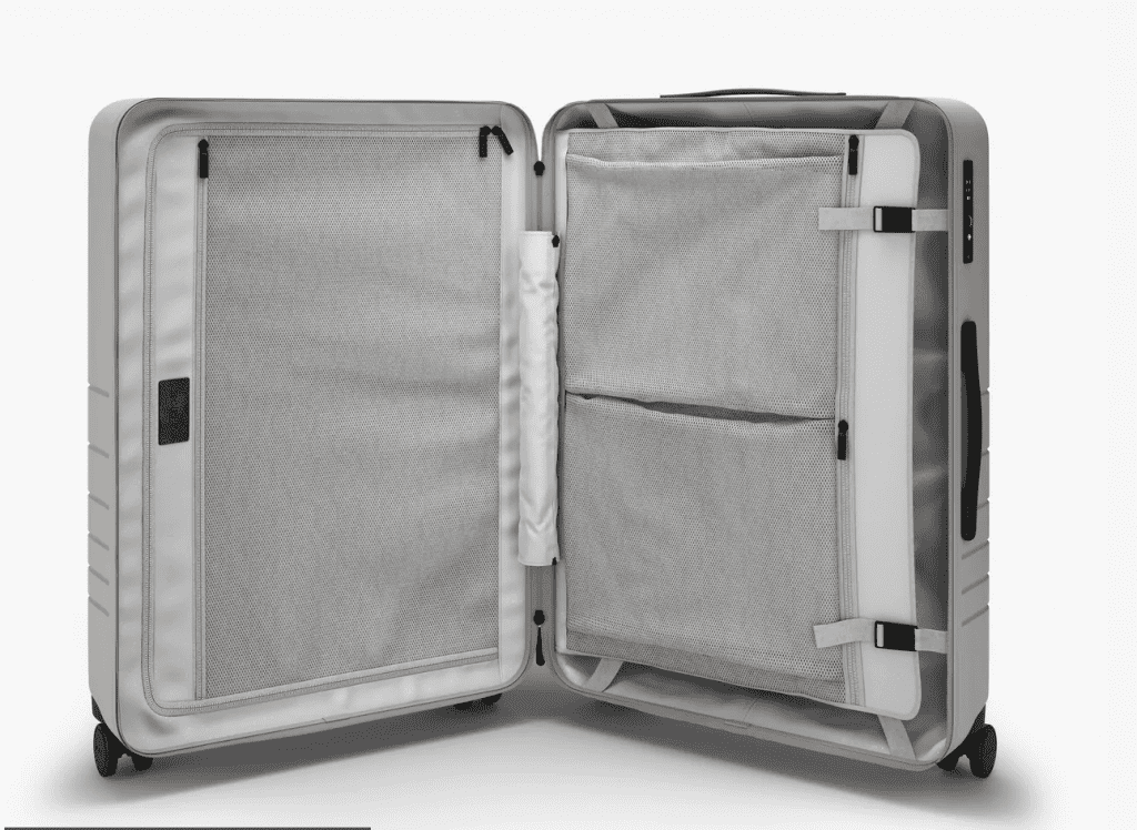 The interior of the Monos Checked Bag features extra pockets and two sides with enclosures. One side is zipped and the other has a compression pad with clips.